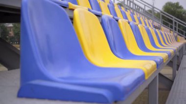 4K, Stadyumdaki Boş Plastik Koltuklar. Seyirci ve Hayranları Olmayan Futbol Stadyumu Tribününde Sarı ve Mavi Koltuklar