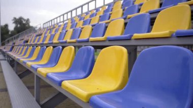 4K, Stadyumdaki Boş Plastik Koltuklar. Seyirci ve Hayranları Olmayan Futbol Stadyumu Tribününde Sarı ve Mavi Koltuklar