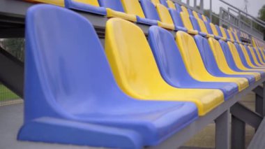 4K, Stadyumdaki Boş Plastik Koltuklar. Seyirci ve Hayranları Olmayan Futbol Stadyumu Tribününde Sarı ve Mavi Koltuklar