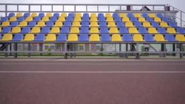 4K, Stadyumdaki Boş Plastik Koltuklar. Seyirci ve Hayranları Olmayan Futbol Stadyumu Tribününde Sarı ve Mavi Koltuklar