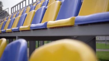 4K, Stadyumdaki Boş Plastik Koltuklar. Seyirci ve Hayranları Olmayan Futbol Stadyumu Tribününde Sarı ve Mavi Koltuklar