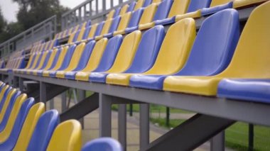 4K, Stadyumdaki Plastik Koltuklar Boş. Seyirci ve Hayranları Olmayan Spor Arenası Tribününde Sarı ve Mavi Koltuklar