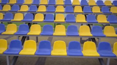 4K, Stadyumdaki Plastik Koltuklar Boş. Seyirci ve Hayranları Olmayan Spor Arenası Tribününde Sarı ve Mavi Koltuklar