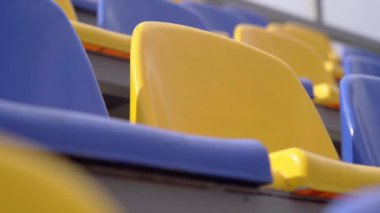 4K, Stadyumdaki Plastik Koltuklar Boş. Seyirci ve Hayranları Olmayan Spor Arenası Tribününde Sarı ve Mavi Koltuklar