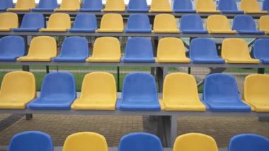 4K, Stadyumdaki Plastik Koltuklar Boş. Seyirci ve Hayranları Olmayan Spor Arenası Tribününde Sarı ve Mavi Koltuklar