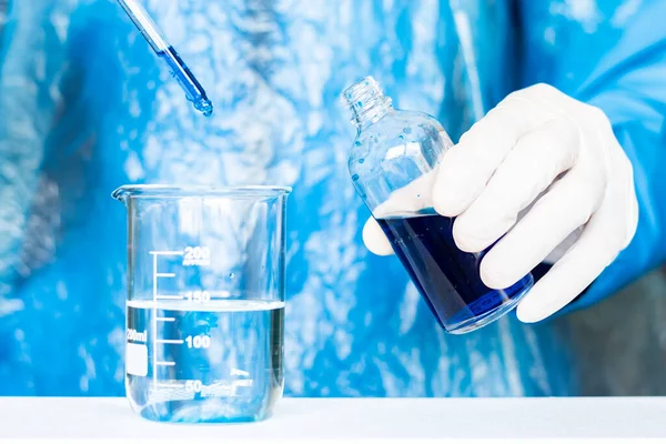 Close-up of a professional male scientist in gloves making experiment with reagents in laboratory. Medicine and research concept