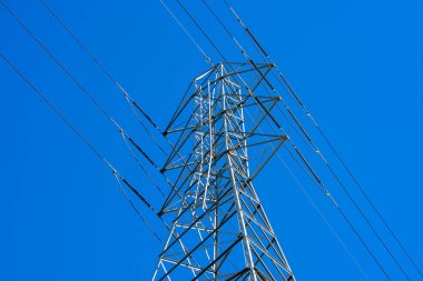 Yüksek voltaj iletim kulesi (elektrik kulesi, elektrik direği, çelik kafes kulesi) mavi gökyüzünde paralel tek devre hatları olan