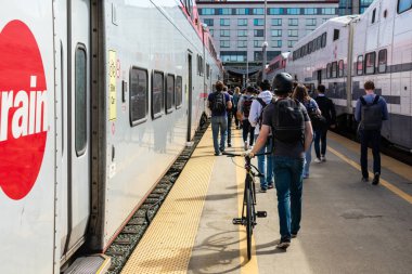 İstasyon çıkışına doğru giden tren peronunda yürüyen bir grup yolcu Caltrain vagonlarından indikten sonra San Francisco, California, ABD - 2019