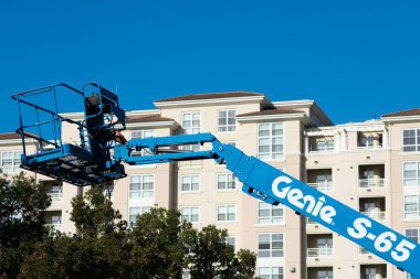 Genie teleskopik patlama kaldırma. Arka planda modern çok katlı apartman kompleksi - San Jose, California, ABD - 2020