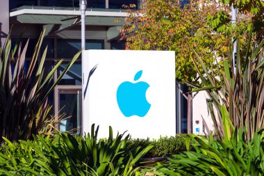 Silikon Vadisi 'ndeki ofislerden birinin girişindeki yeşil peyzaj üzerinde Apple logosu - Cupertino, California, ABD - 2020