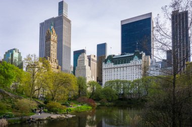 Arkasında ağaçlar, göl ve Manhattan gökdelenleri olan Central Park.