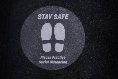 Kaldırımda güvenli bir tabela var. Covid-19 sosyal mesafeyi korumakla ilgili uyarı