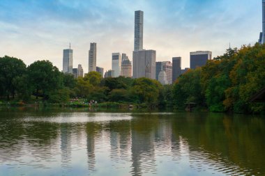 Central Park 'ın göl suyundaki yansıma. Arka planda ağaçlar ve gökdelenler var.