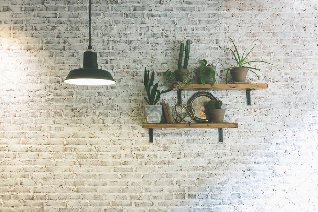 Modern stylish white brick wall with shelves and plants. Hanging lighting lamp giving creating ambient