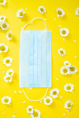 Tıbbi maske ve sarı, güneşli arka planda beyaz papatyalar..