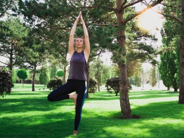 Parkta yoga. Kafkasyalı orta yaşlı kadın dışarıda egzersiz yapıyor.