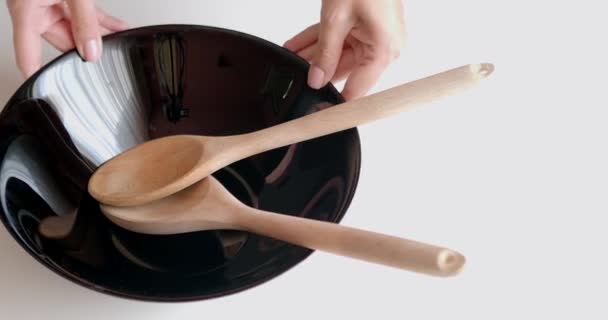 Mangkuk hitam untuk salad di latar belakang putih dengan sendok kayu untuk pencampuran — Stok Video