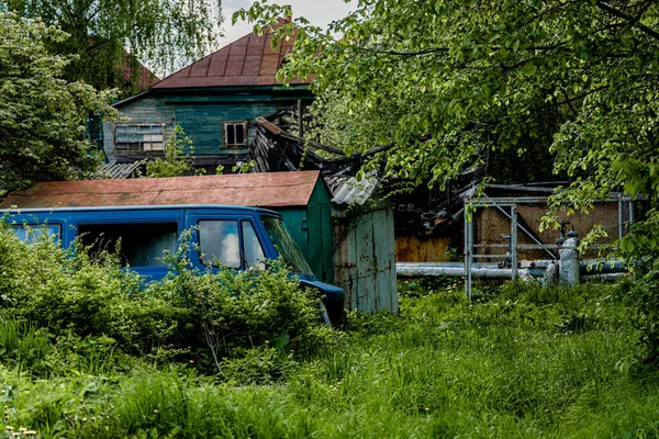 Velho carro destruído azul no pátio de uma casa de aldeia — Fotografia de Stock