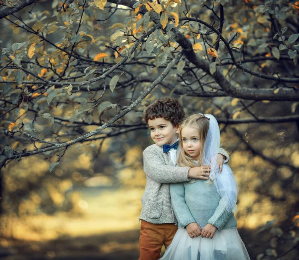 Chlapec a dívka oblečeni jako nevěsta a ženich stojí pod jabloní — Stock fotografie