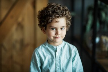 Karanlık bir arka planda kıvırcık bir çocuğun portresi.