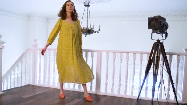 노란 드레스 사진 스튜디오에서에서 카메라 포즈에 밝은 긍정적인 소녀 — 비디오