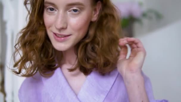 Alegre chica positiva posando para la cámara en un traje púrpura de pie en una escalera blanca — Vídeo de stock