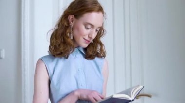 Holding ve beyaz oda bir kitap okuma genç Kızıl saçlı kız