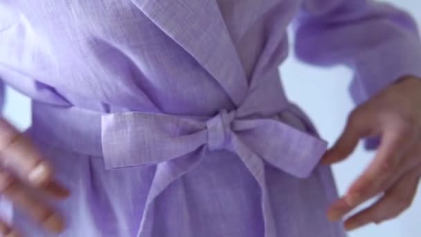 Detalles de primer plano del nudo del lazo del vestido púrpura de la mujer sobre fondo blanco — Vídeo de stock