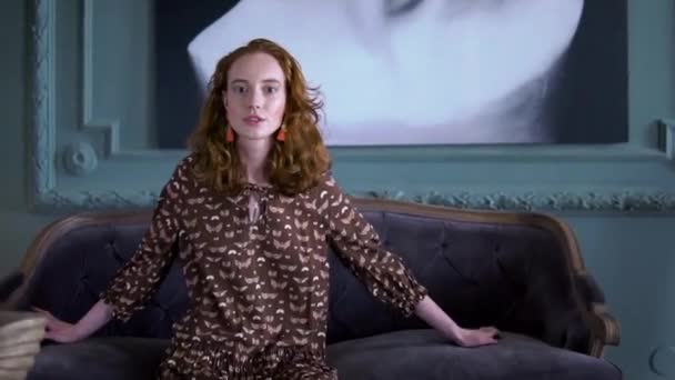 Fröhliches positives Mädchen posiert auf der Couch sitzend vor der Kamera — Stockvideo