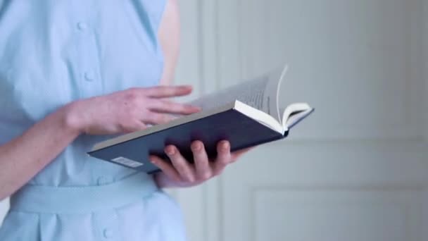 Joven pelirroja sosteniendo y leyendo un libro en habitación blanca — Vídeos de Stock