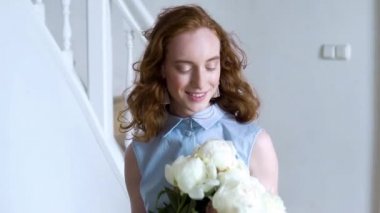 Güzel kırmızı saçlı kız portresi yakından beyaz peonies büyük bir çalı burnunu çekmek