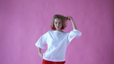 neşeli pozitif sarışın kız bir fotoğraf stüdyosu pembe bir arka plan üzerinde kamera için poz