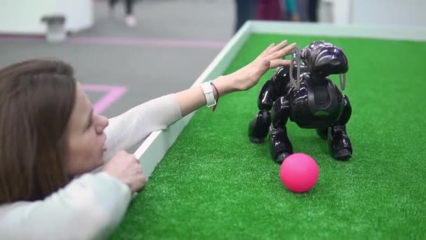 Flicka som leker med en robot i form av en hund på en utställning — Stockvideo