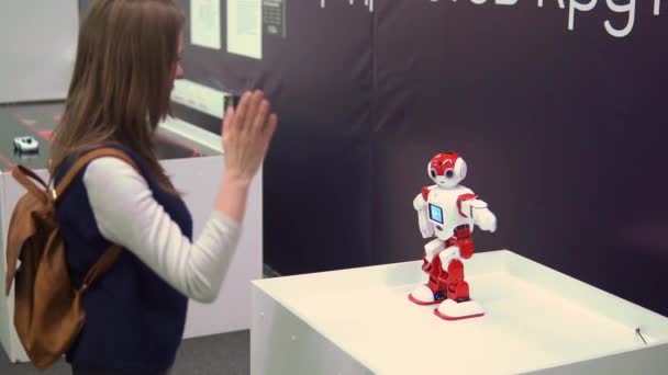 Молодая девушка играет с игрушкой робота на выставке — стоковое видео