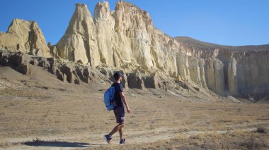 genç bir gezgin bir dağlık alanda bir yolda yürüyor