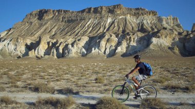 Genç adam bir manzara dağlar ile bir arka plan üzerinde bir bisiklet sürme