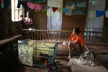 Siargao, Filipinler - 18 Mart 2016: Evde köpek ve tavuklarla yaşayan filipinli aile aynı odada yaşıyor