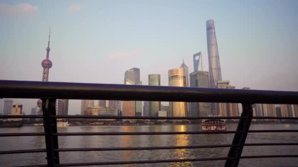 Shanghai, China-15 januari 2018: prachtige stads stad met glazen wolkenkrabbers staande langs de Huangpu-rivier tegen de achtergrond van de ondergaande zon. De rivier wordt gevaren door pleziervaartuigen — Stockvideo