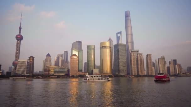 Hermoso paisaje urbano con rascacielos de cristal a lo largo del río Huangpu sobre el telón de fondo del sol poniente. El río es navegado por embarcaciones de recreo — Vídeos de Stock