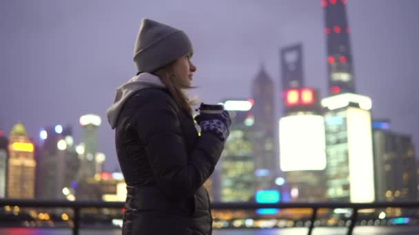 Młoda dziewczyna w czarnej Kurtki i kapelusz spacery po pięknym Szanghaju z kawą w dłoniach — Wideo stockowe