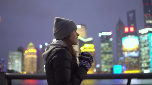 Молодая девушка в черной куртке и шляпе ходит по красивому Шанхаю с кофе в руках — стоковое видео