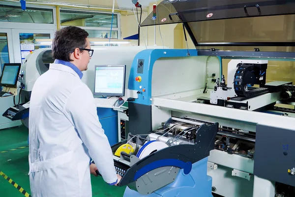 Beyaz cüppe ve gözlüklü mühendis Surface Mount Technology makinesiiçin çalışıyor. Cnc makinepcb işleme, yüksek teknoloji fabrikasında elektronik bileşenlerin üretimi