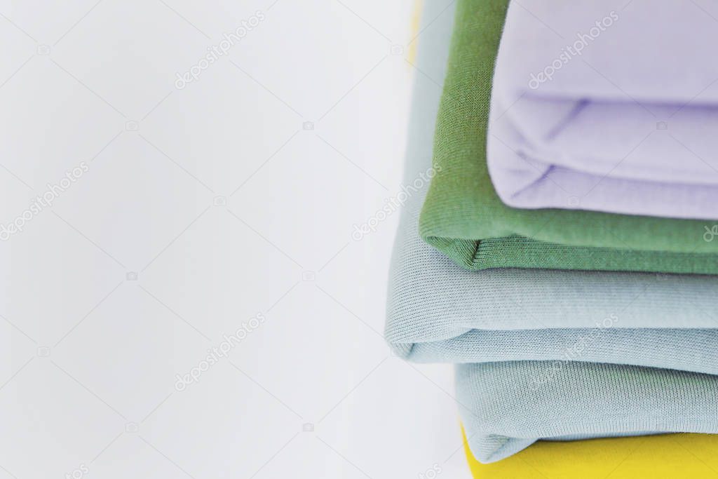 A stack of fabrics for sewing on the table. Multi-colored fabrics for tailoring. A pile of fabrics for sewing clothes