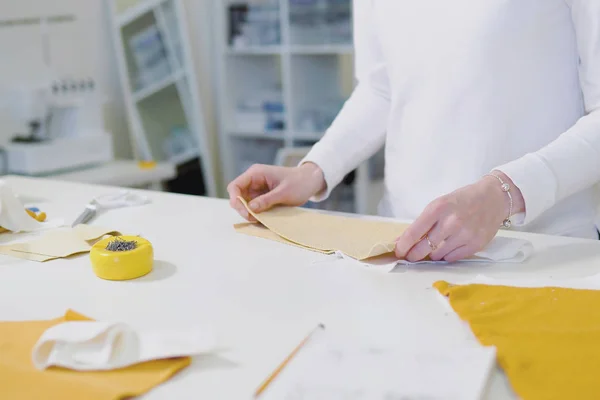 Modedesigner eller tailoress skärande tyg medan du arbetar med ritning skiss, material på Worktable. Kläd affärsidé. utsikt från toppen — Stockfoto