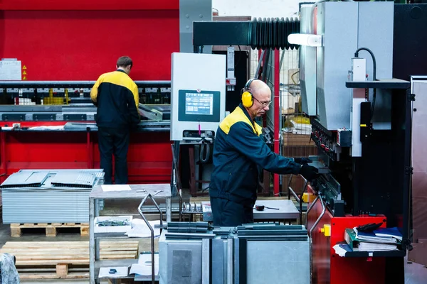 Worker operator bending metal sheet process by sheet bending machine for bus manufactuing part, steel folding with machine