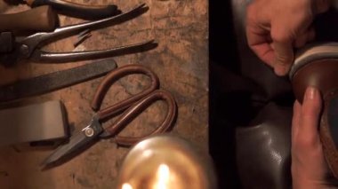 Ayakkabıcı erkekler için ayakkabı yapar. Tabanını parlatıyor.