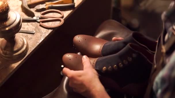 빈티지 효과가 있는 신발을 만들기 위해 가죽을 가공하는 과정에서 숙련 된 제화 업자와 함께 일 했던 고대 작업장 — 비디오