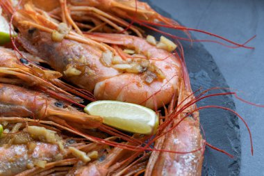 Siyah tabakta limonlu ve sarımsaklı kızarmış gambonlar.