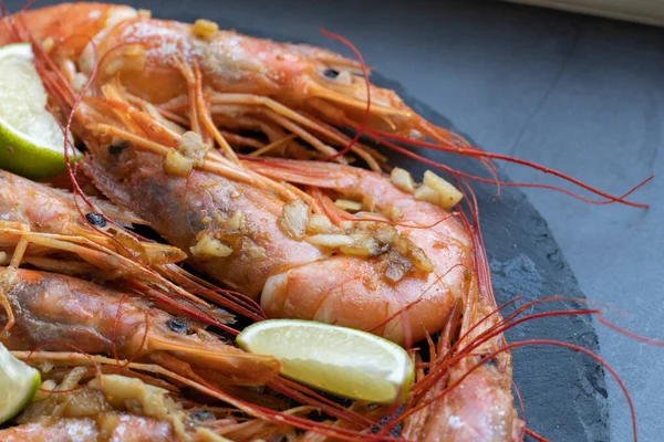 Siyah tabakta limonlu ve sarımsaklı kızarmış gambonlar.