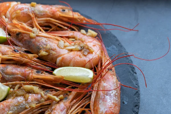 Siyah tabakta limonlu ve sarımsaklı kızarmış gambonlar.